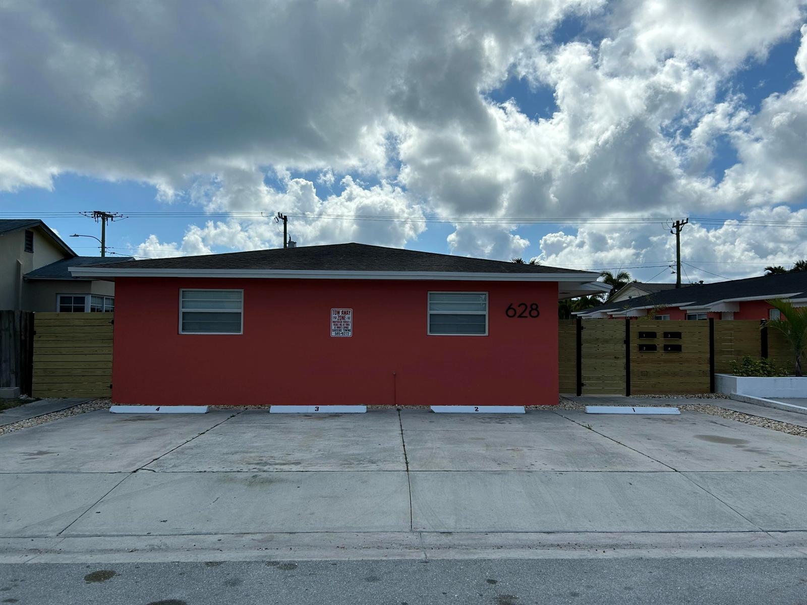 A red exterior building with four numbered parking spaces and a wooden fence — 628 N M Street, FL 33460, FL