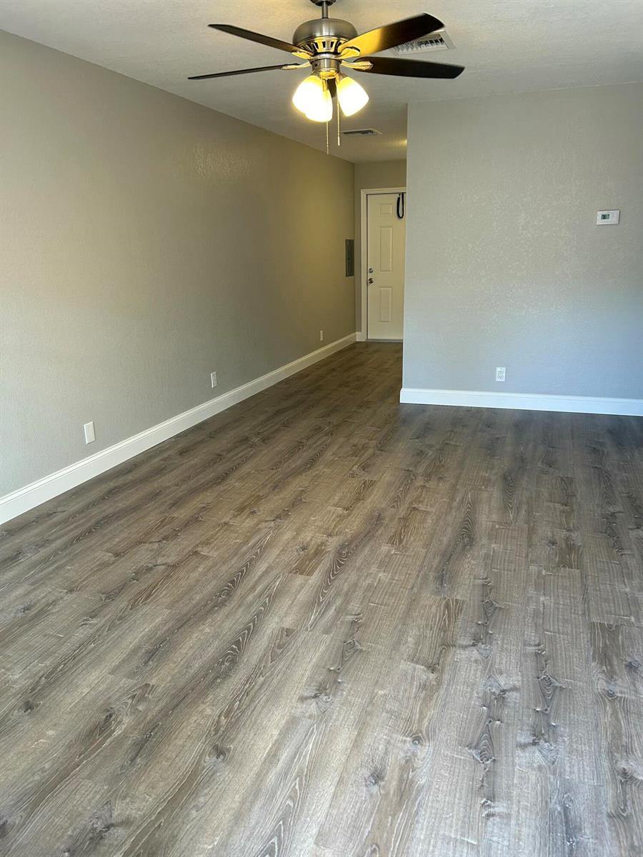 An empty room features gray walls, wood-look flooring, a ceiling fan, and a white door — 628 N M Street, FL 33460, FL