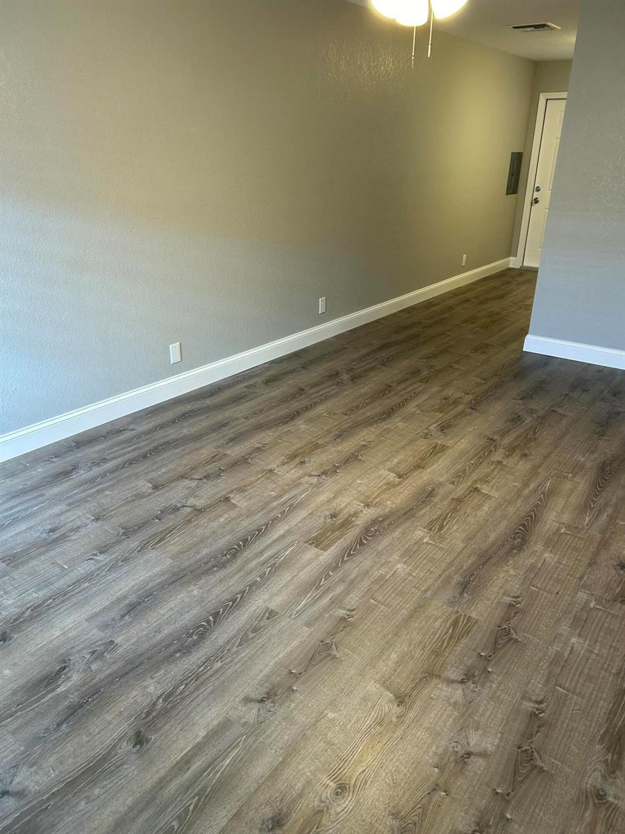 An empty room features gray walls, white baseboards, and wood-look vinyl plank flooring — 628 N M Street, FL 33460, FL