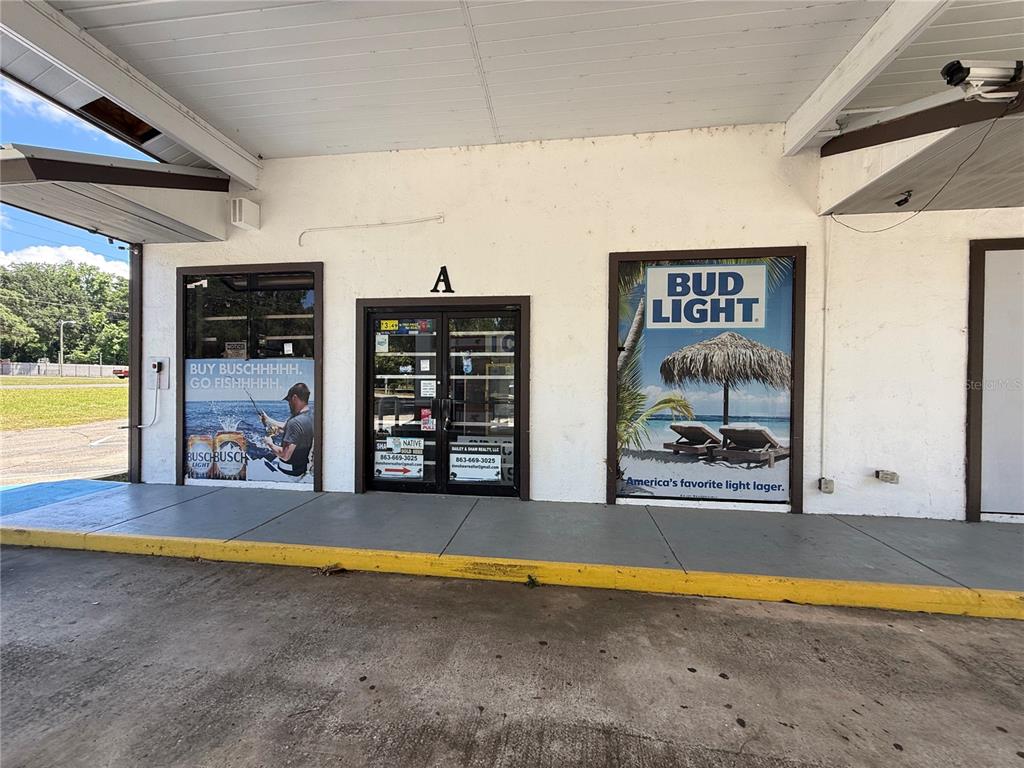 The exterior of a commercial building features a glass entrance door and two large advertisements — 3380 SE LAKE WEIR AVENUE UNIT A, OCALA, FL