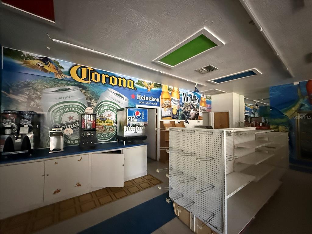 A retail space features a beverage counter with branded wall murals and empty display shelving — 3380 SE LAKE WEIR AVENUE UNIT A, OCALA, FL