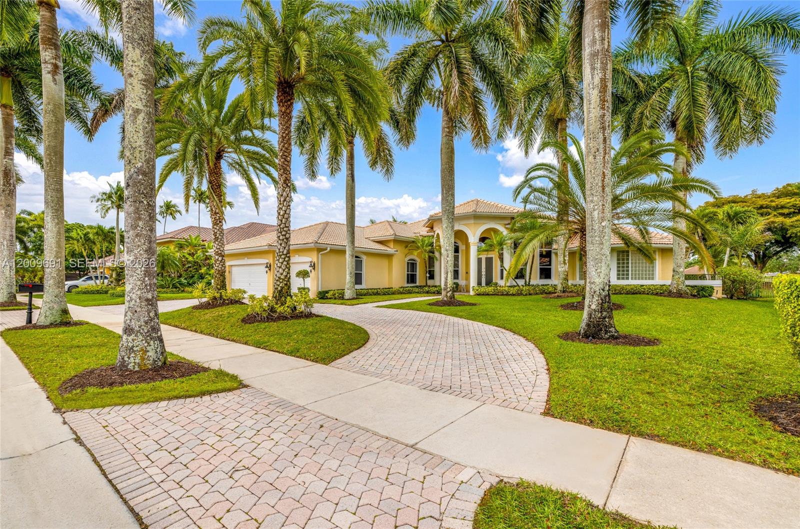A yellow single-story house with a paved driveway and palm trees in the front yard — 2477 Poinciana Dr, Weston FL 33327, WESTON, FL