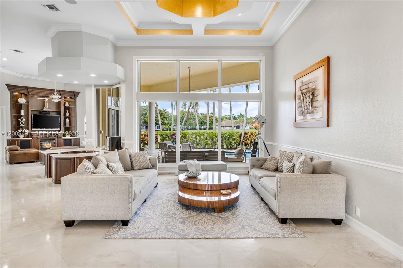 A living room features two beige sofas, a tiered wooden coffee table, and large windows — 2477 Poinciana Dr, Weston FL 33327, WESTON, FL