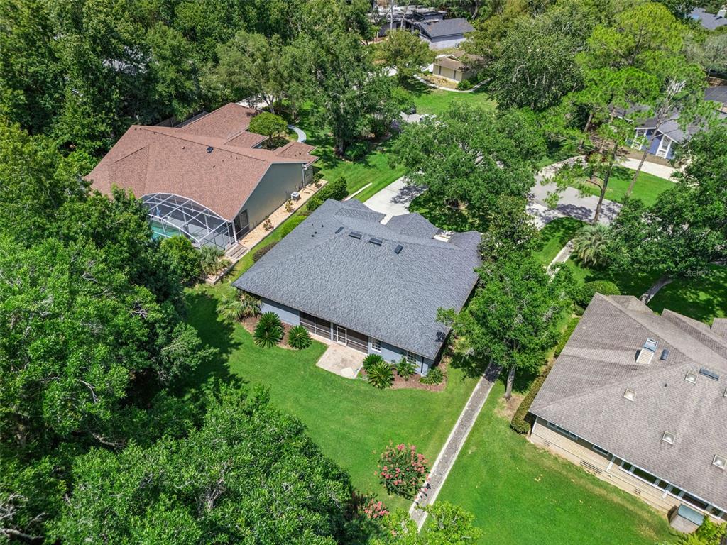 An aerial view shows three suburban houses surrounded by dense green trees and lawns — 148 WISTERIA DRIVE, LONGWOOD, FL