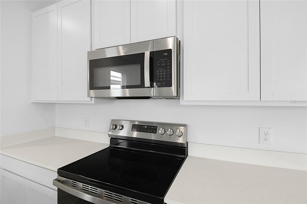 A kitchen features white cabinets, a stainless steel microwave, and a black electric range — 6174 DAPHNE STREET, LAKE HAMILTON, FL