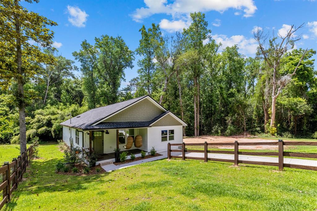 A small, white house with a covered porch and shingled gable sits in a yard — 618 N STEWART STREET, QUINCY, FL