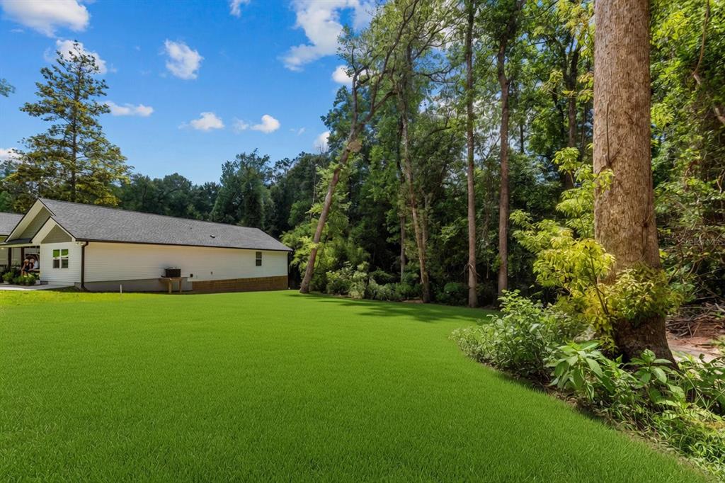 A white house with a gray roof sits beside a large, manicured green lawn — 618 N STEWART STREET, QUINCY, FL