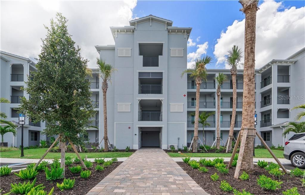 A paved walkway leads to the entrance of a multi-story, light blue apartment building — 14041 HERITAGE LANDING BOULEVARD UNIT 642, PUNTA GORDA, FL