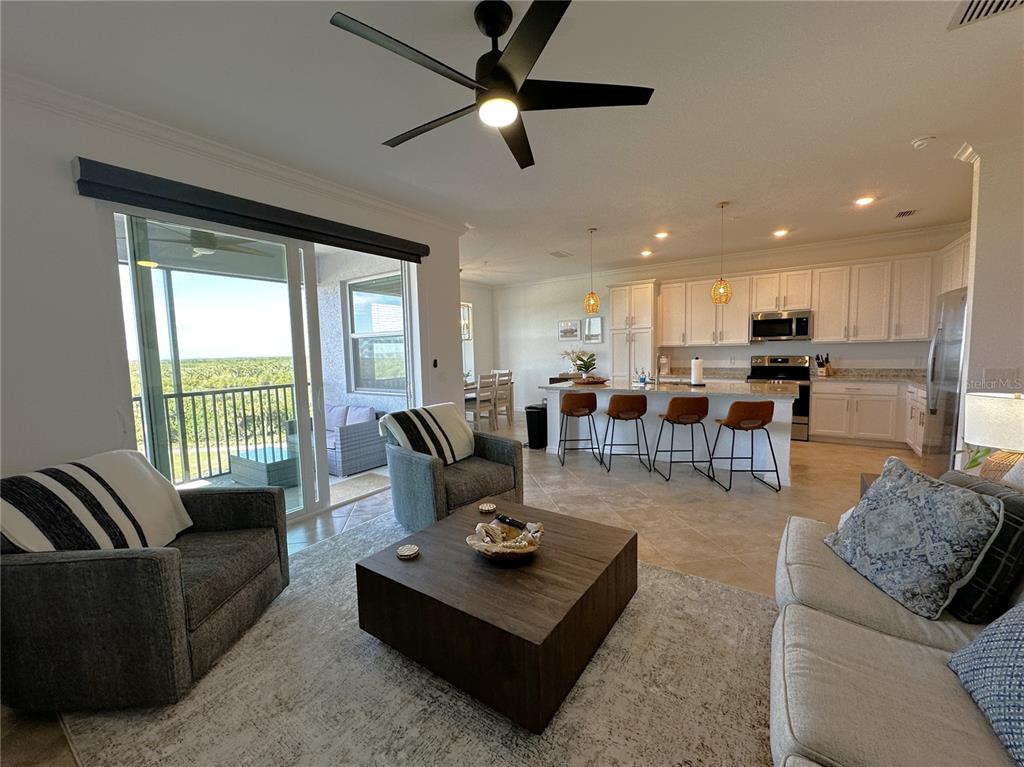 An open-concept living room and kitchen featuring tile floors, a large island, and balcony access — 14041 HERITAGE LANDING BOULEVARD UNIT 642, PUNTA GORDA, FL