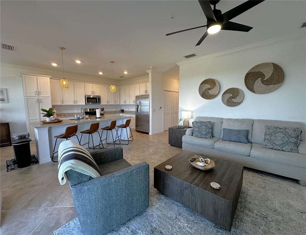 An open-concept living room and kitchen featuring white cabinetry, a breakfast bar, and neutral furniture — 14041 HERITAGE LANDING BOULEVARD UNIT 642, PUNTA GORDA, FL