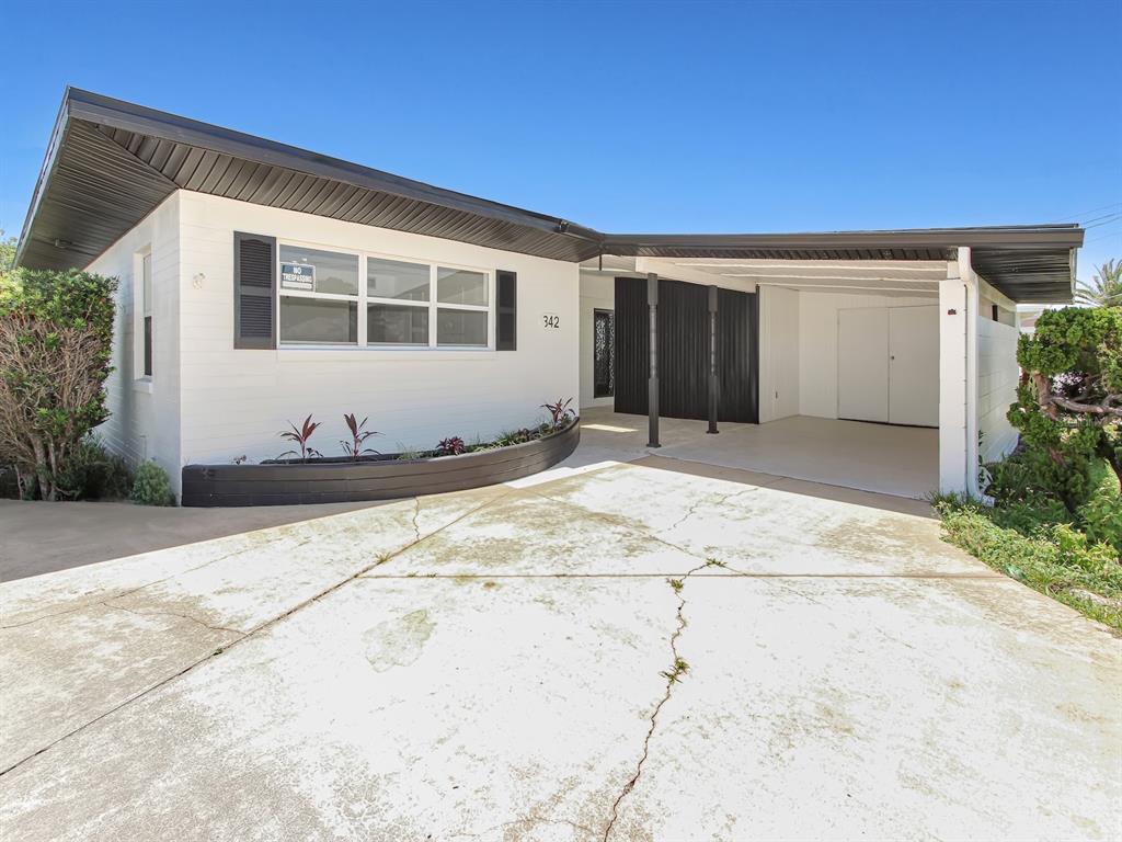 A white single-story house features a dark roof, a carport, and a cracked concrete driveway — 342 BOYLSTON AVENUE, DAYTONA BEACH, FL