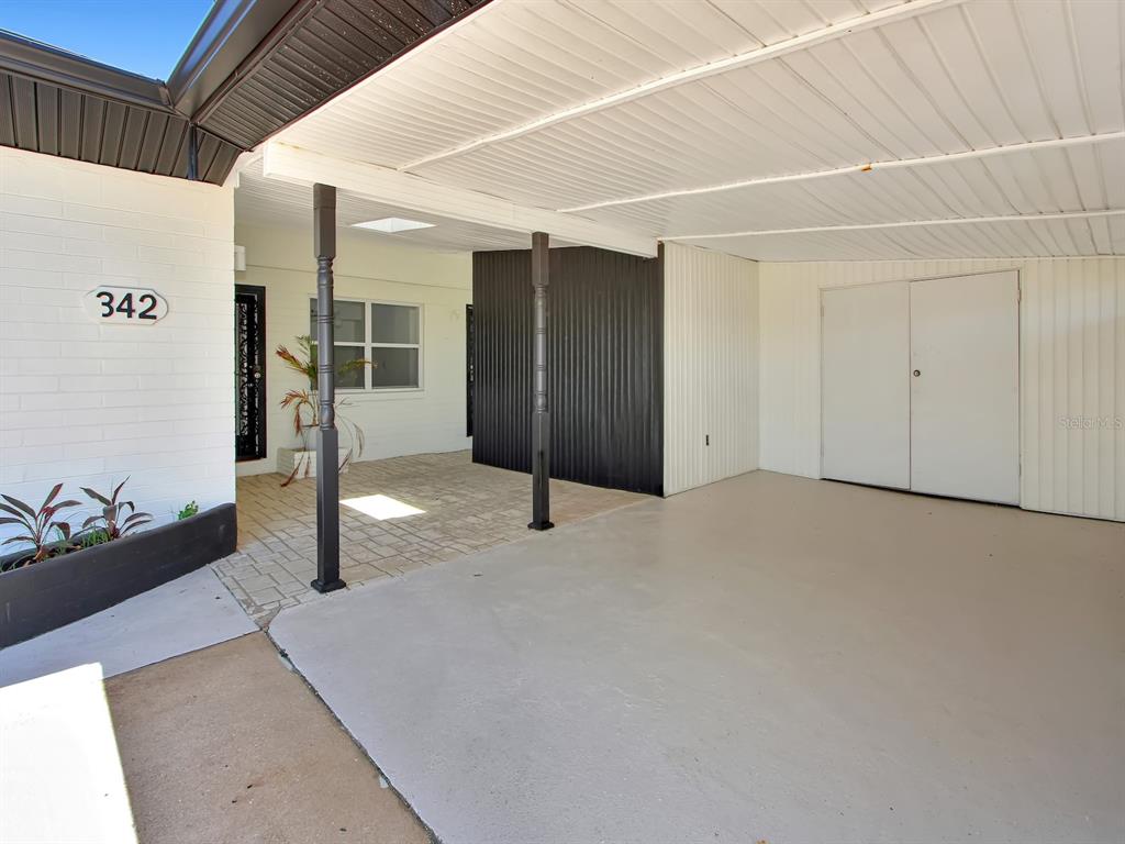 A covered carport with a concrete floor, white siding, and two dark support columns — 342 BOYLSTON AVENUE, DAYTONA BEACH, FL
