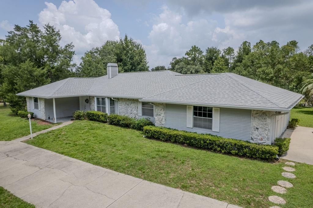 A single-story house with light gray siding, stone accents, and a gray shingled roof — 9501 SW 207TH CIRCLE, DUNNELLON, FL