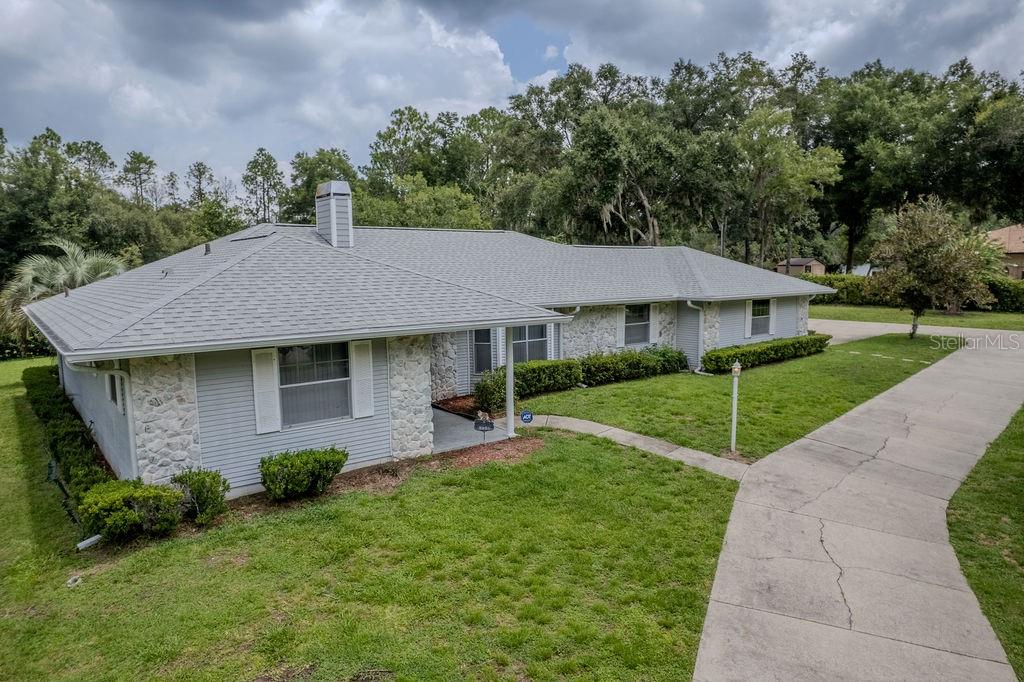 A single-story house with light gray siding, stone accents, and a concrete driveway — 9501 SW 207TH CIRCLE, DUNNELLON, FL