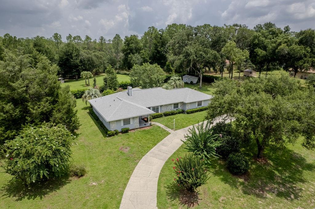 An aerial view shows a single-story house with a light-colored roof and a curved driveway — 9501 SW 207TH CIRCLE, DUNNELLON, FL
