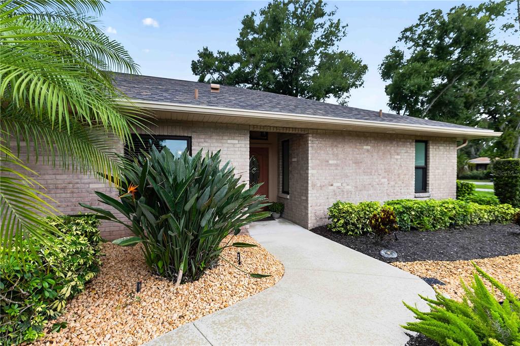 A brick house exterior features a concrete walkway leading to the front entrance — 9703 65TH AVENUE E, BRADENTON, FL