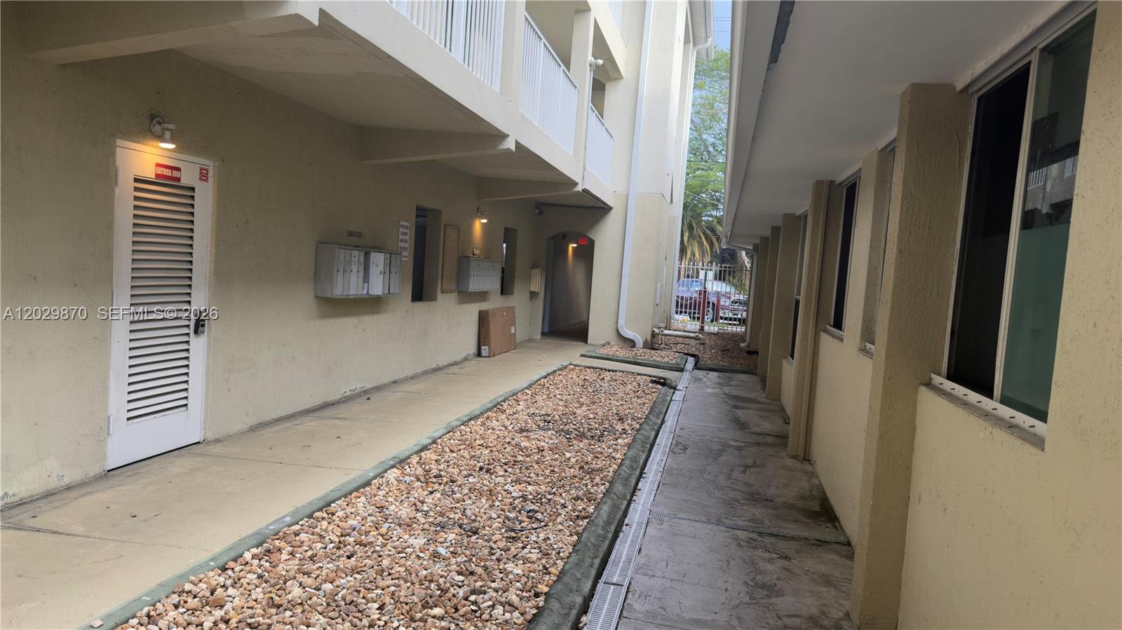 A narrow outdoor walkway between two apartment buildings features a gravel garden and mailboxes — 1025 SW 7th Ave # 6, Miami FL 33130, MIAMI, FL