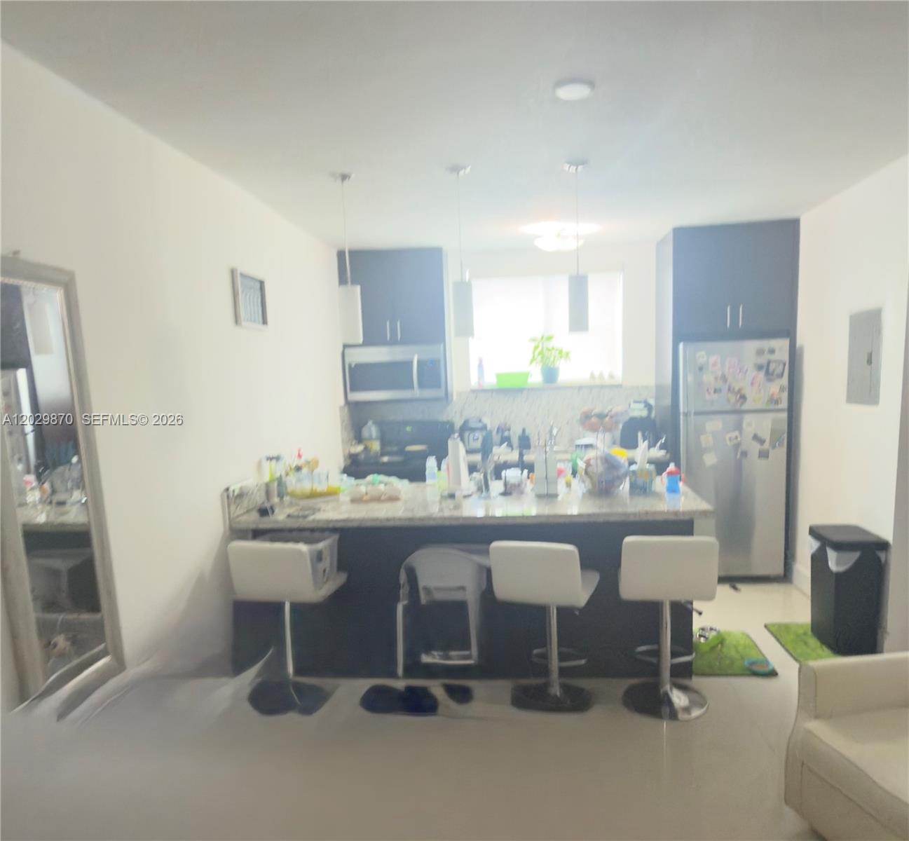 A kitchen features dark cabinetry, a granite-topped island with bar stools, and stainless steel appliances — 1025 SW 7th Ave # 6, Miami FL 33130, MIAMI, FL
