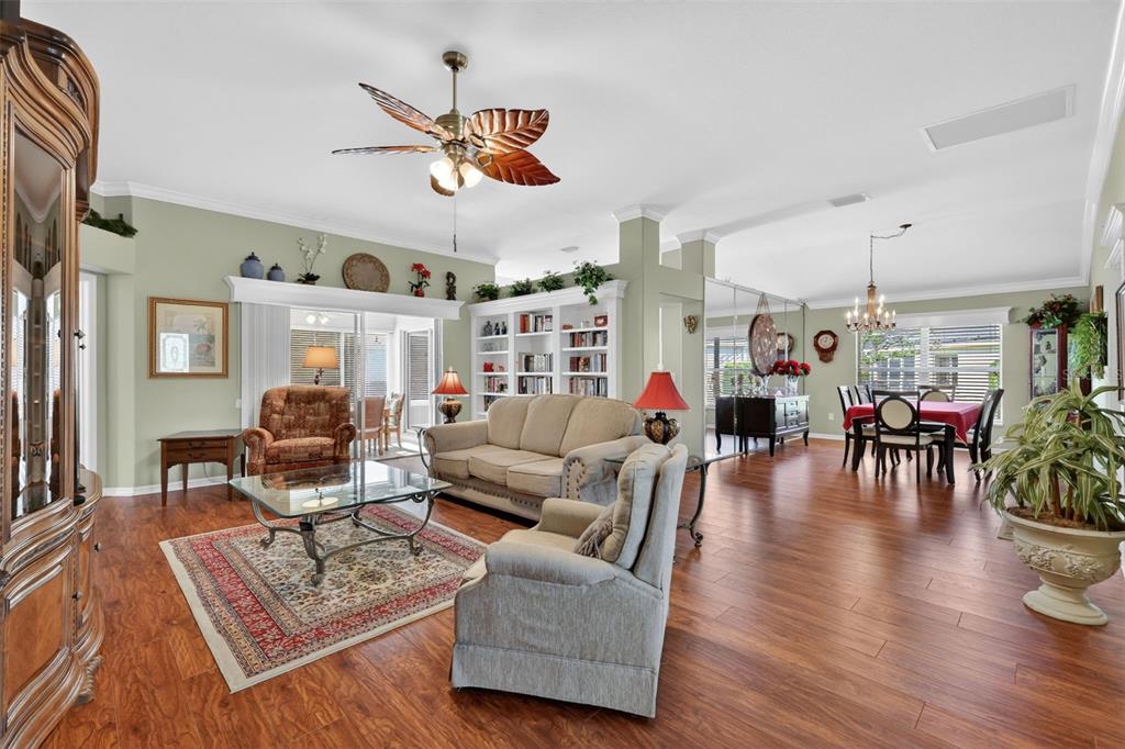 A living room with wood floors, a ceiling fan, and an adjacent dining area — 3183 KEARNS CORNER, THE VILLAGES, FL