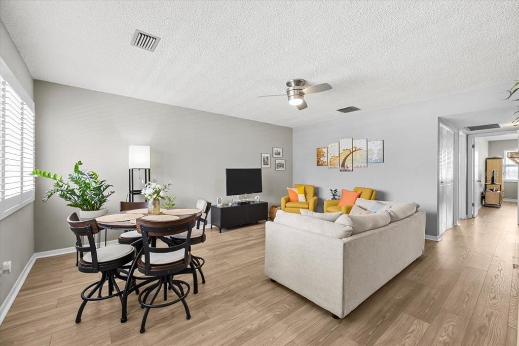 A living and dining area features light wood flooring, a beige sofa, and yellow chairs — 1235 S HIGHLAND AVENUE UNIT 2-307, CLEARWATER, FL