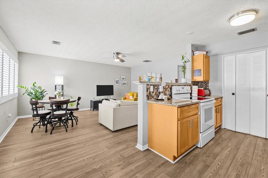 An open-concept living and dining area features wood-look flooring and a kitchen with light cabinets — 1235 S HIGHLAND AVENUE UNIT 2-307, CLEARWATER, FL