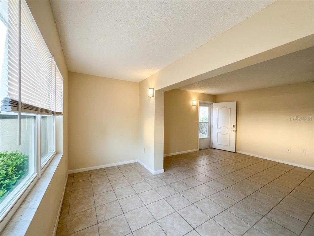 An empty room with beige walls, tile flooring, and a white door leading outside — 1103 CYPRESS GARDENS BOULEVARD UNIT 30, WINTER HAVEN, FL