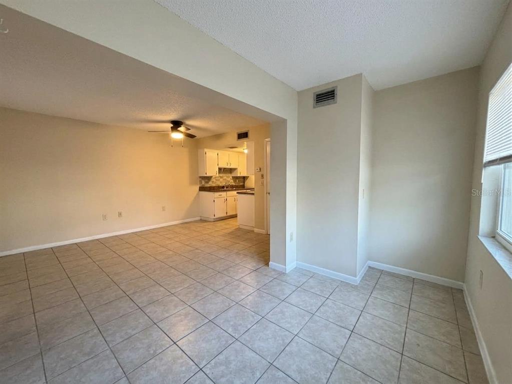An open-concept living area with tile flooring leads into a kitchen with white cabinets — 1103 CYPRESS GARDENS BOULEVARD UNIT 30, WINTER HAVEN, FL