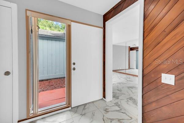 An entryway features white marble-look tile flooring, a white door, and diagonal wood wall paneling — 1502 NE BUCKEYE ROAD NE UNIT 2, WINTER HAVEN, FL