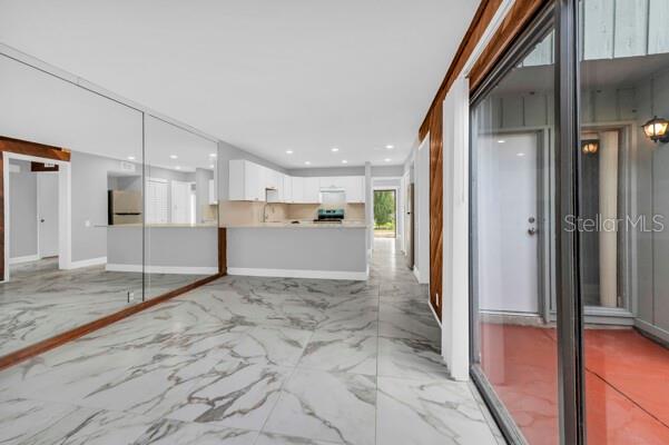 A kitchen with white cabinets and marble-look tile flooring viewed from a glass sliding door — 1502 NE BUCKEYE ROAD NE UNIT 2, WINTER HAVEN, FL