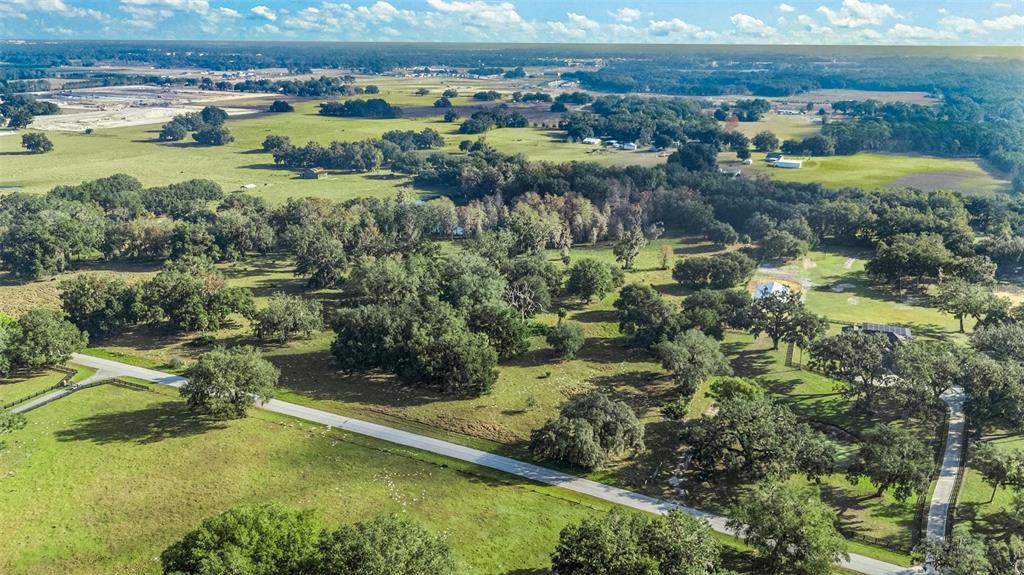 An aerial view shows a rural landscape with a paved road, scattered trees, and pastures — TRACT 2 - CR 221, WILDWOOD, FL