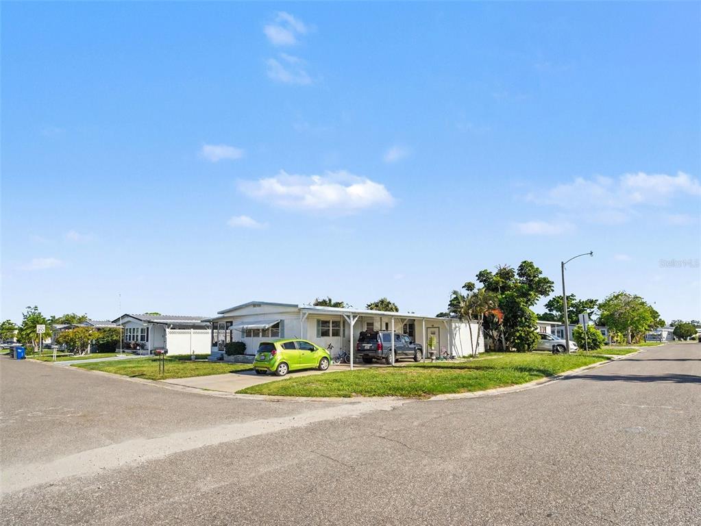 A single-story manufactured home with a carport and a green car parked in front — 309 50TH AVENUE TERRACE E, BRADENTON, FL