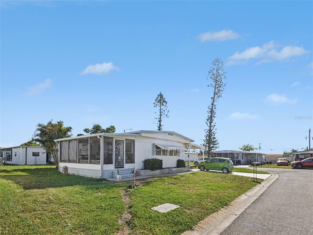 A white mobile home with a screened-in porch sits on a grassy lot — 309 50TH AVENUE TERRACE E, BRADENTON, FL