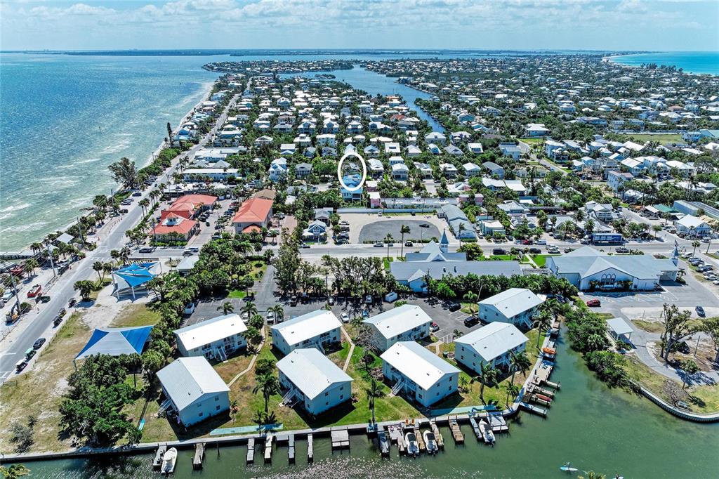 An aerial view shows a coastal neighborhood with houses, a marina, and a white-circled building — 517 SPRING AVENUE, ANNA MARIA, FL