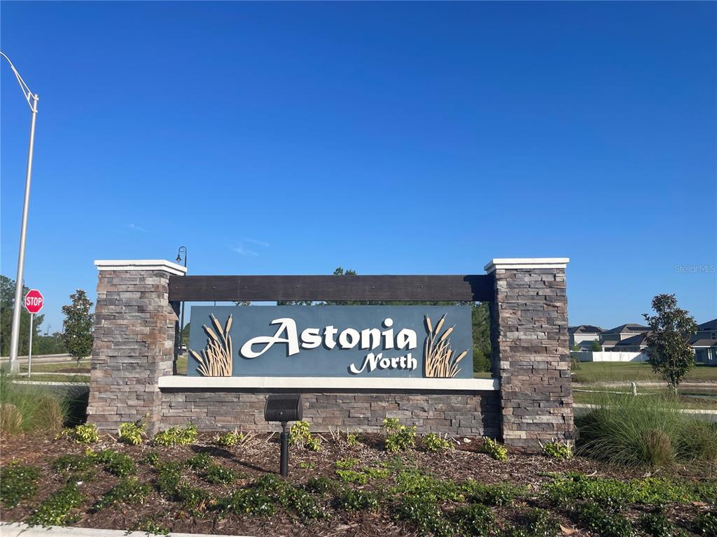 A stone-clad monument sign for the Astonia North community stands against a clear blue sky — 922 JACKSON AVE, DAVENPORT, FL