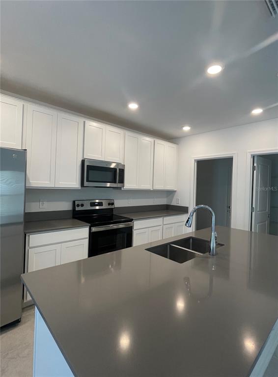A kitchen features white cabinets, gray countertops, a stainless steel stove, and a center island — 922 JACKSON AVE, DAVENPORT, FL