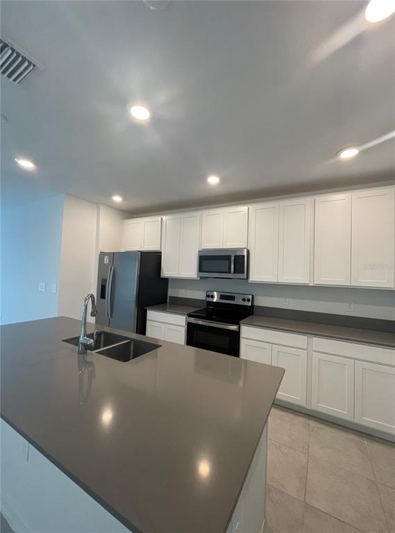 A modern kitchen features white cabinets, stainless steel appliances, and a large gray quartz island — 922 JACKSON AVE, DAVENPORT, FL