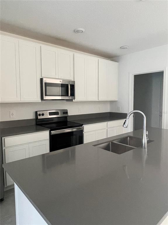 A kitchen features white cabinets, gray countertops, a stainless steel microwave, and a center island — 922 JACKSON AVE, DAVENPORT, FL
