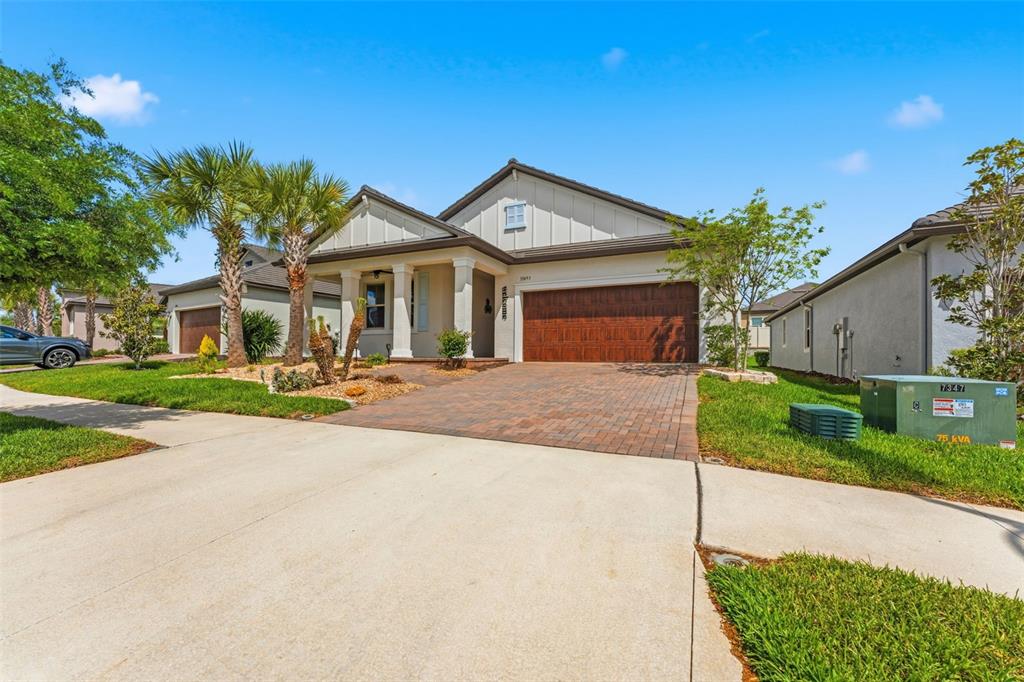 A single-story suburban house with a brick driveway, two-car garage, and a covered front porch — 31493 CANNON RUSH DRIVE, SAN ANTONIO, FL