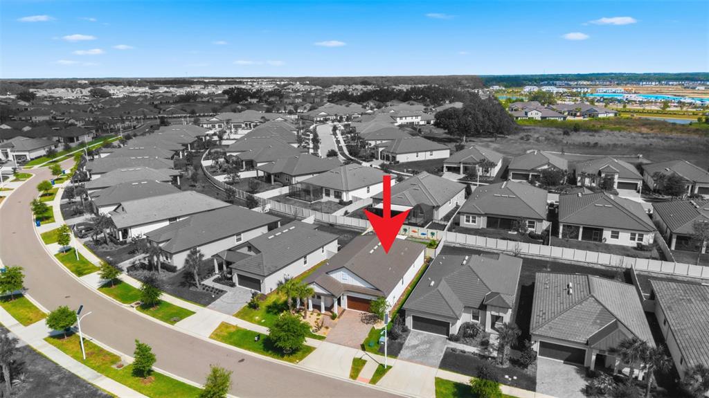 An aerial view shows a suburban house with a red arrow pointing to its roof — 31493 CANNON RUSH DRIVE, SAN ANTONIO, FL
