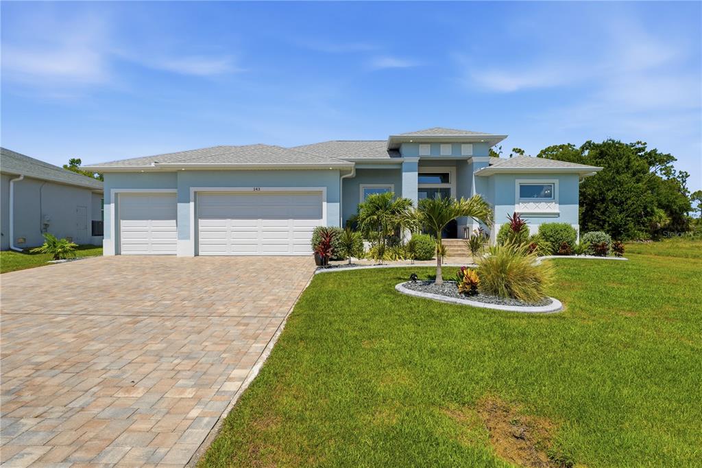 A light blue single-story house with a paver driveway and a three-car garage — 143 LONG MEADOW LANE, ROTONDA WEST, FL