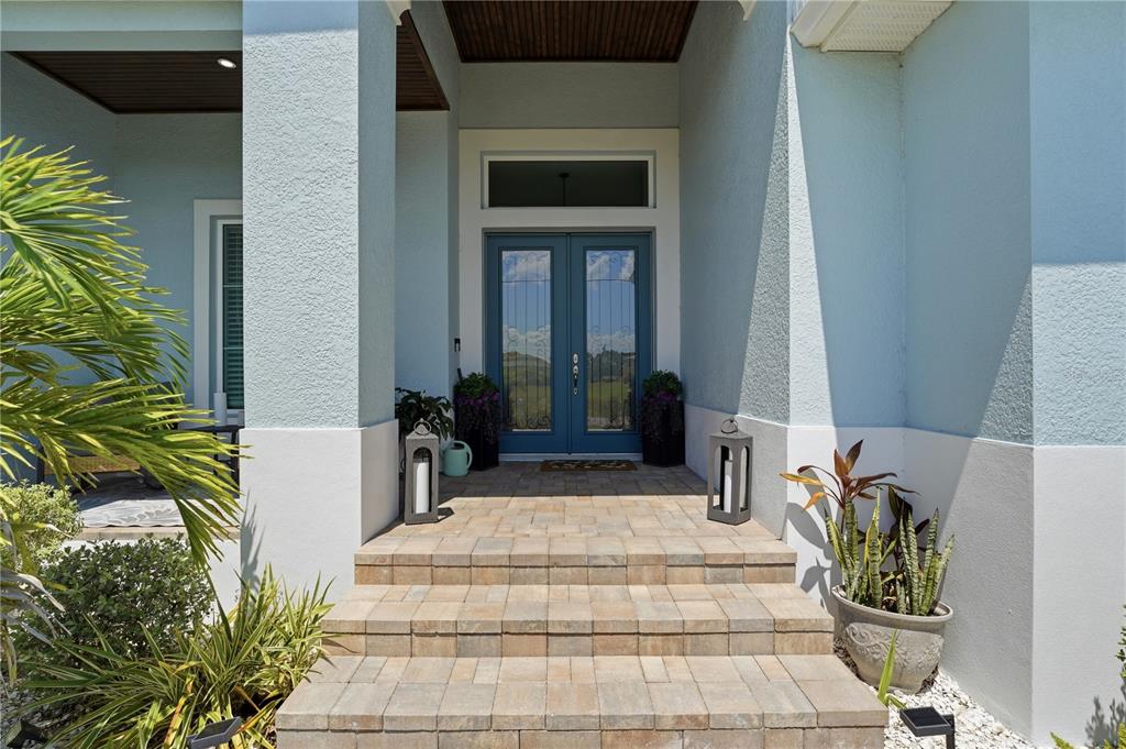 A blue double front door is accessed by stone steps leading to a covered entryway — 143 LONG MEADOW LANE, ROTONDA WEST, FL