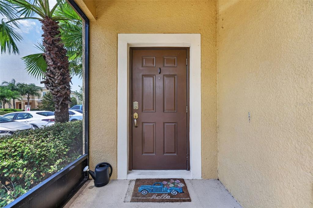 A two-story tan stucco townhouse with a brown garage and a screened-in side porch — 1702 IVORY GOOSE PLACE, RUSKIN, FL