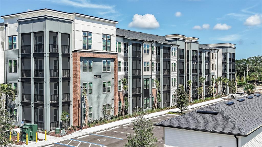 A multi-story apartment building with screened balconies and a parking lot in the foreground — 35820 N US HWY 19 UNIT C1, PALM HARBOR, FL