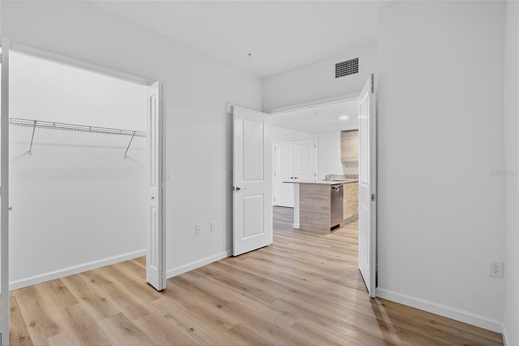 A room with light wood-look flooring features a walk-in closet and an open doorway — 1230 SOUTHSTATION PLACE UNIT 312, ORLANDO, FL