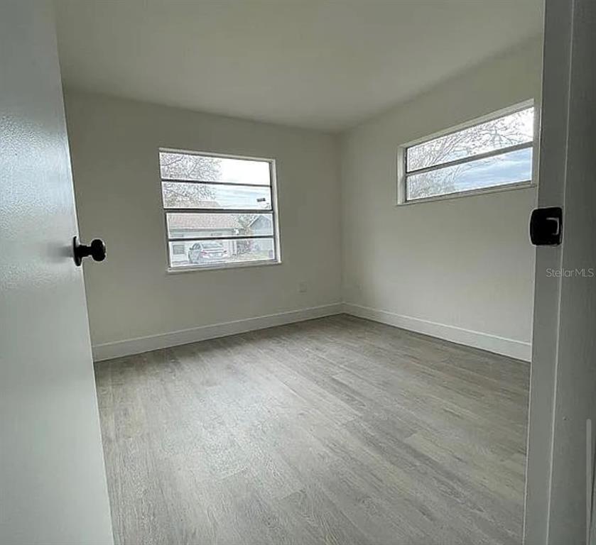 An empty bedroom features white walls, light wood-look flooring, and two windows — 1227 WATERVIEW BOULEVARD W, LAKELAND, FL