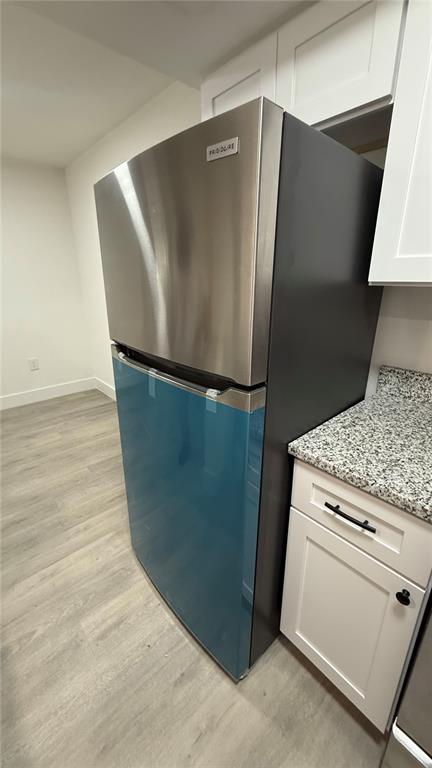 A stainless steel Frigidaire refrigerator with protective blue film stands in a kitchen with cabinets — 1227 WATERVIEW BOULEVARD W, LAKELAND, FL