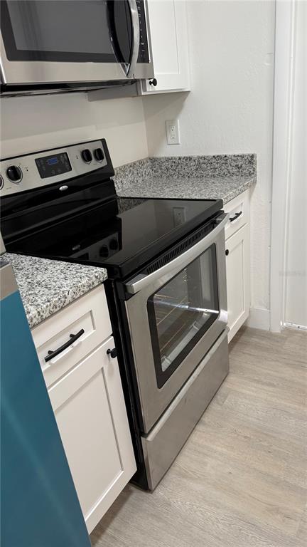 A kitchen features stainless steel appliances, white cabinets, and speckled granite countertops — 1227 WATERVIEW BOULEVARD W, LAKELAND, FL