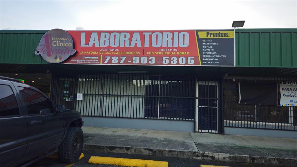 The exterior of a clinical laboratory building features a large sign with contact information — Km 11.0 PR-175, TRUJILLO ALTO, PR