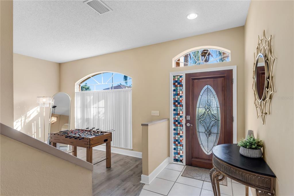An entryway features a wooden front door, a foosball table, and a decorative wall mirror — 11436 GEORGETOWN CIRCLE, TAMPA, FL