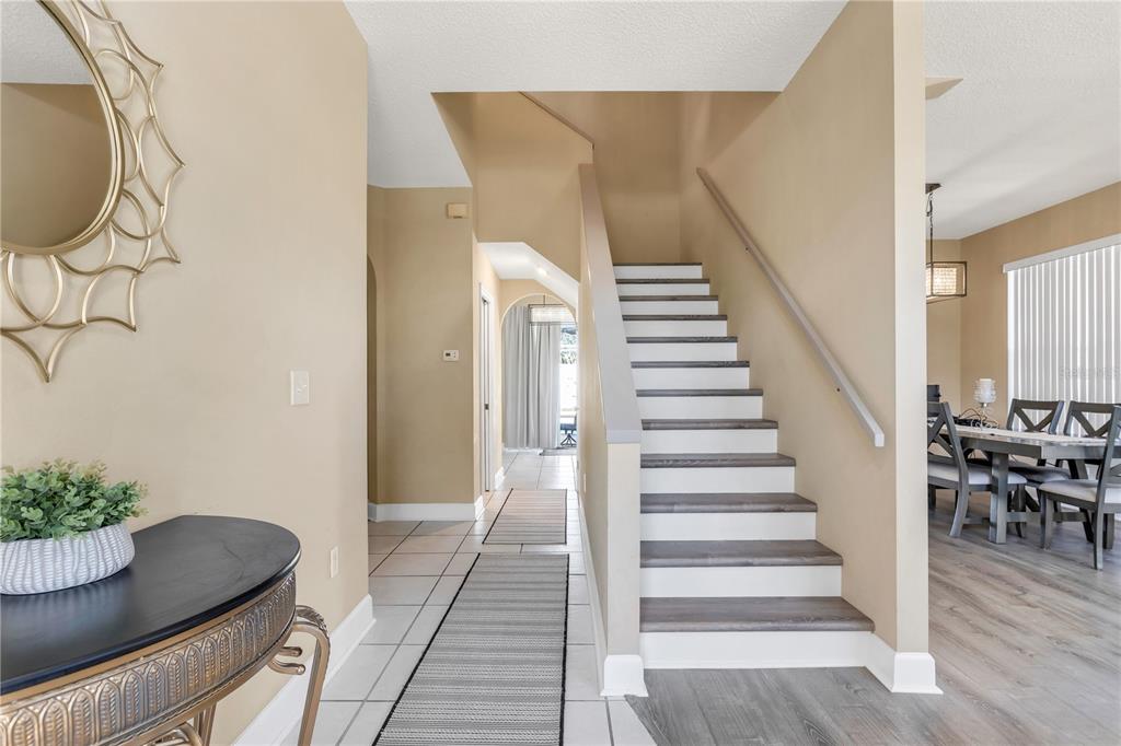 A foyer features a staircase with wood treads, tile flooring, and a console table — 11436 GEORGETOWN CIRCLE, TAMPA, FL